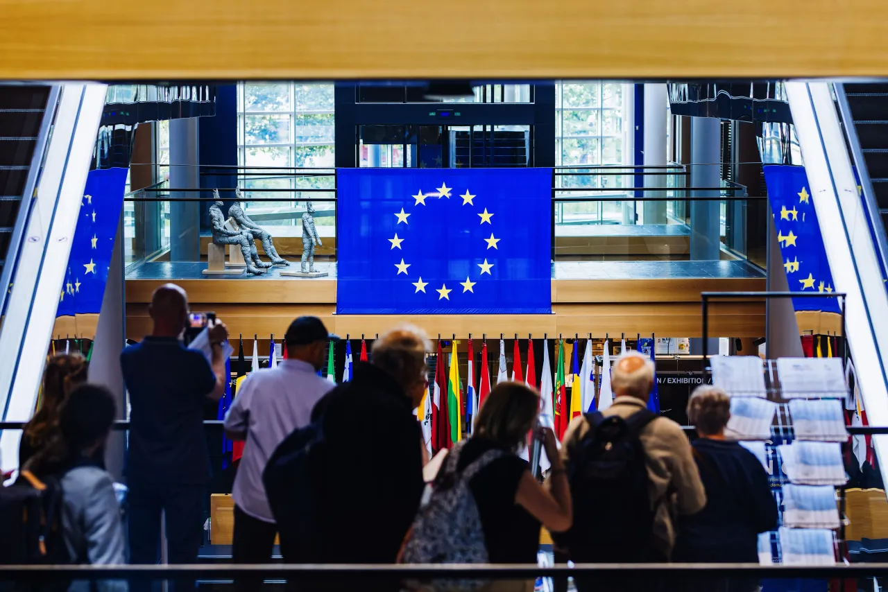 A group of visitors stands in the European Parliament building while the flag of the European Union can be seen in the background.(Photo by Philipp von Ditfurth/picture alliance via Getty Images)