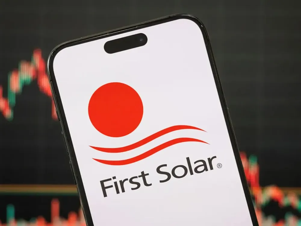 In this photo illustration, the logo of First Solar, Inc. is displayed on a smartphone screen, with the company's latest stock price performance and candlestick chart visible in the background. 