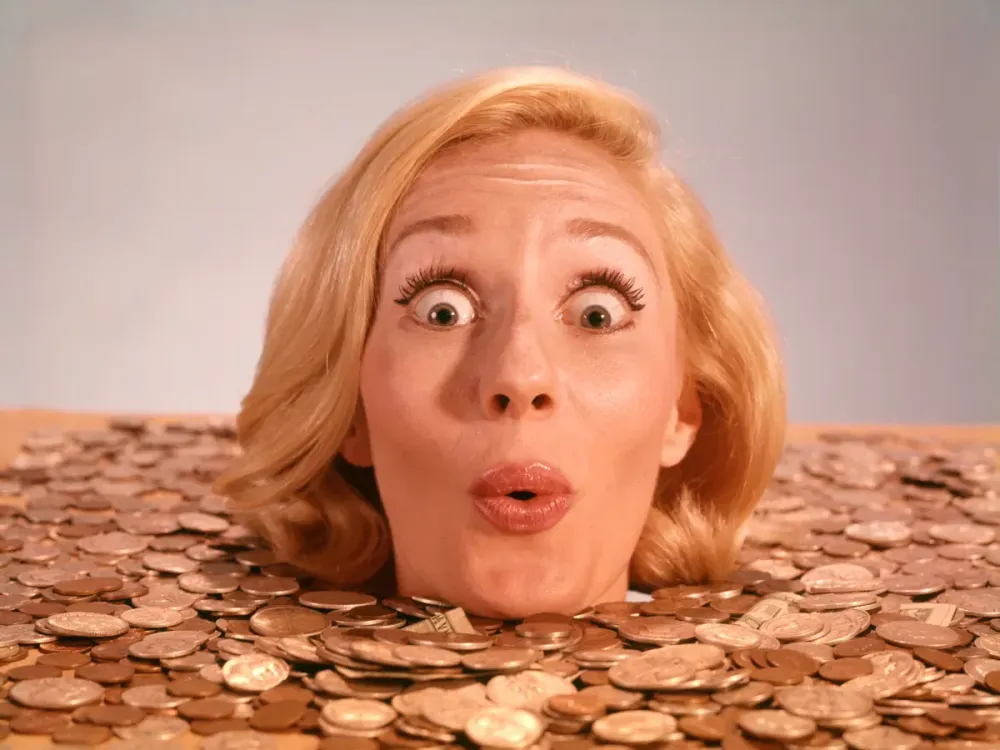 Representative image: 1960s Silly wacky expression on funny woman up to neck in coins and currency drowning in luck. (Photo by H. Armstrong Roberts/ClassicStock/Getty Images)