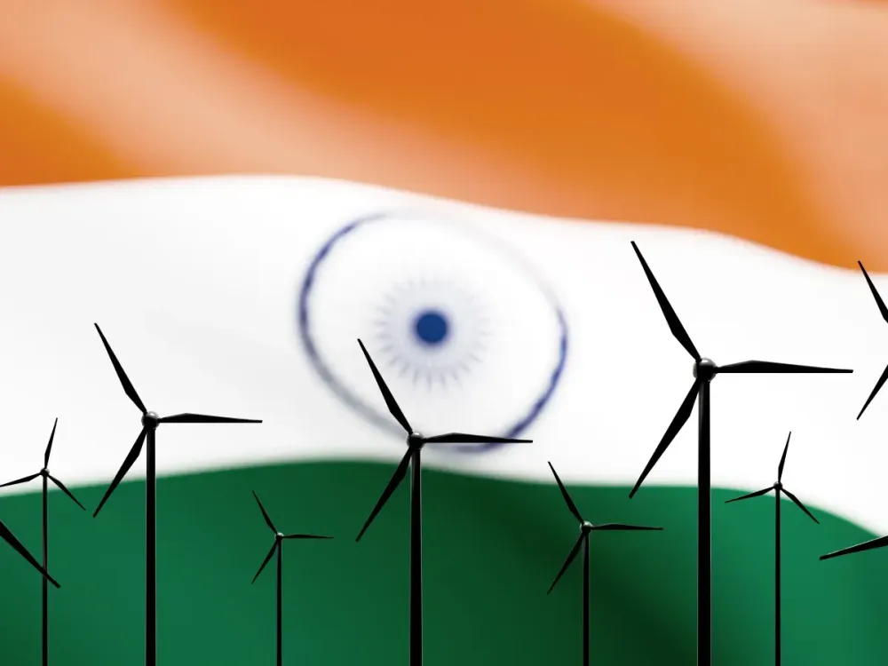 Wind turbines rise against the vibrant orange, white, green, and blue of the Indian flag. | Image source: Getty Images