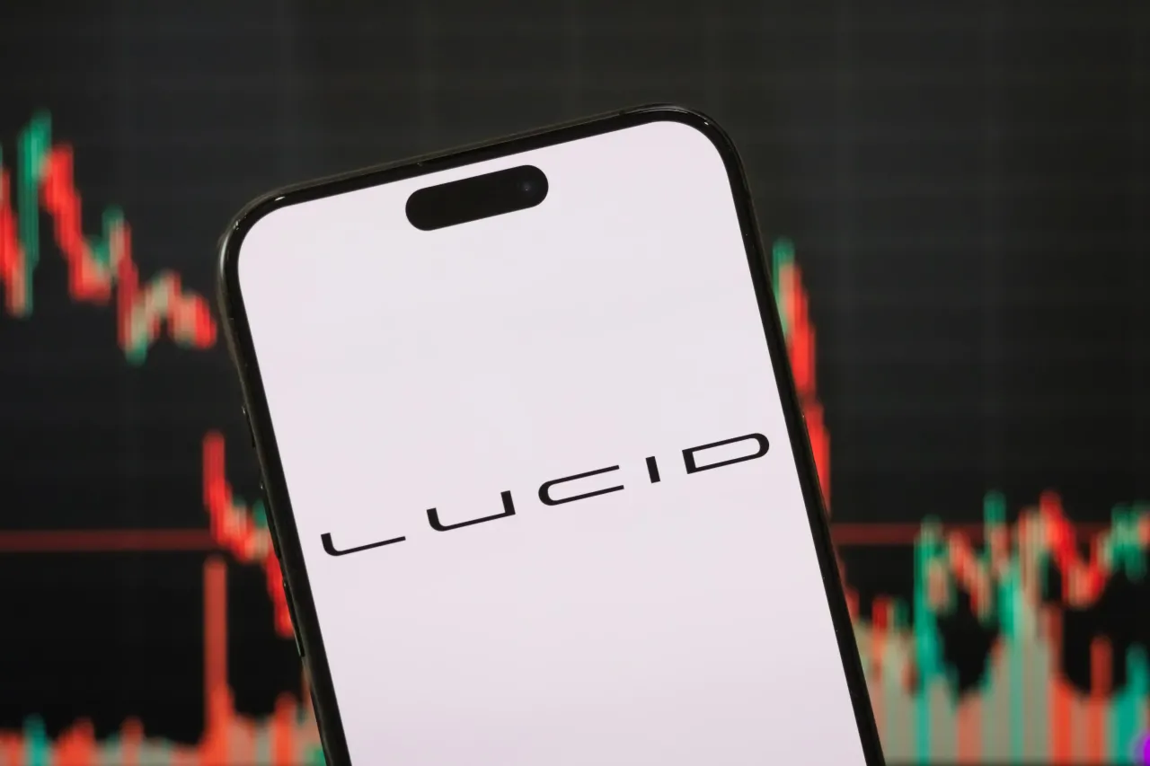 In this photo illustration, the logo of Lucid Group, Inc. is displayed on a smartphone screen, with a stock market chart in the background, on May 4, 2025, in Chongqing, China. (Photo illustration by Cheng Xin/Getty Images)