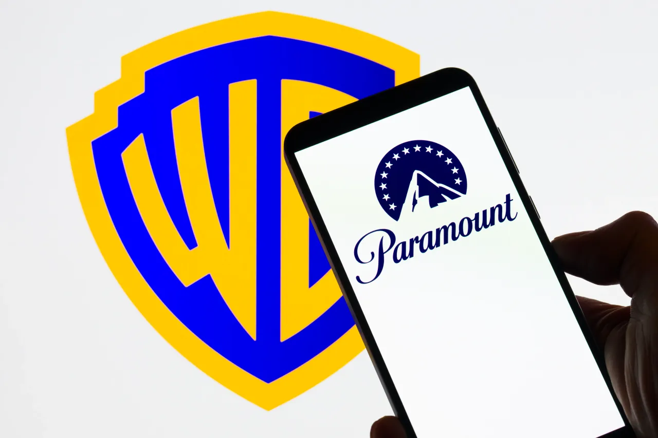 The Paramount logo is displayed on a mobile phone with the Warner Bros. Discovery icon seen in the background