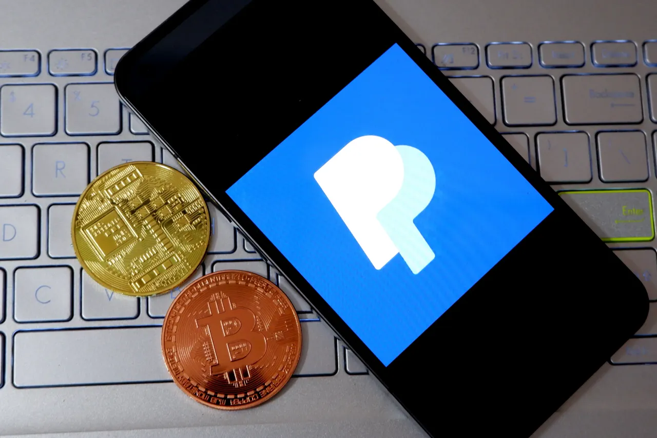 In this photo illustration, a Paypal logo is seen displayed on a smartphone next to cryptocurrency coins. (Photo Illustration by Avishek Das/SOPA Images/LightRocket via Getty Images)