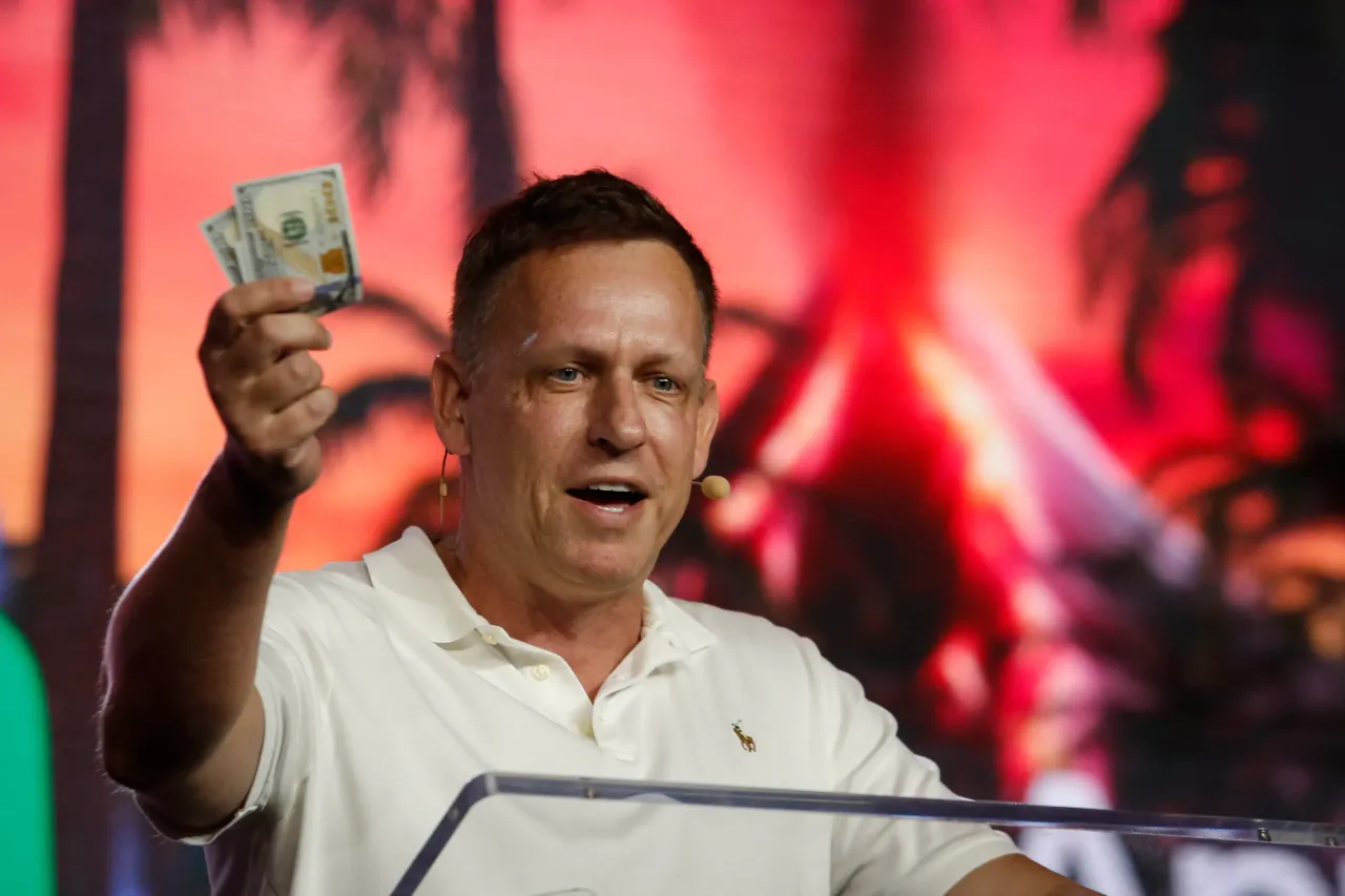 Peter Thiel, co-founder of PayPal, Palantir Technologies, and Founders Fund, holds hundred dollar bills as he speaks during the Bitcoin 2022 Conference at Miami Beach Convention Center on April 7, 2022. (Photo by Marco Bello/Getty Images)