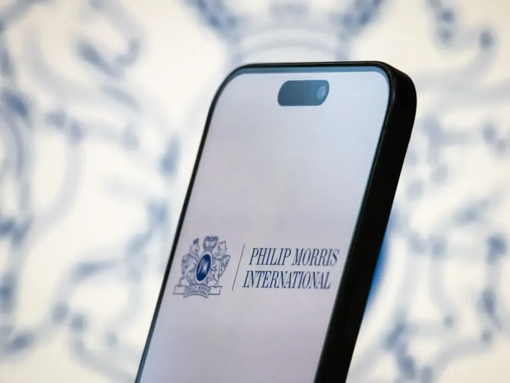In this photo illustration, the logo of Philip Morris International Inc. is displayed on a smartphone screen, with the company's branding in the background, on April 20, 2025, in Chongqing, China. (Photo by Cheng Xin/Getty Images)
