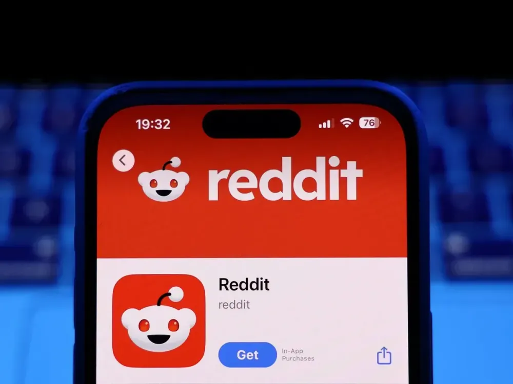 A laptop keyboard and Reddit on App Store displayed on a phone screen are seen in this illustration photo