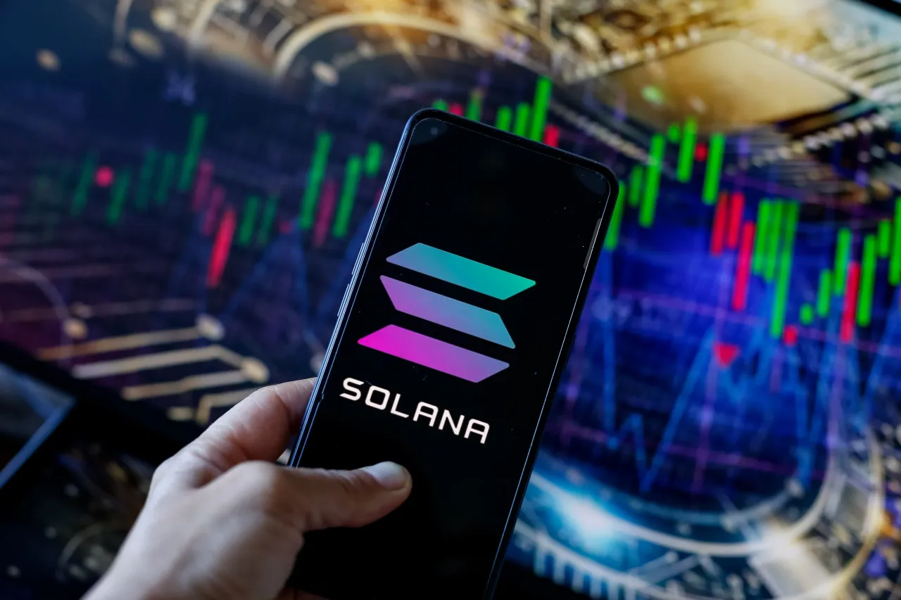 In this photo illustration, the Solana (SOL) logo seen displayed on a smartphone with stock market graphs in the background. (Photo Illustration by Dominika Zarzycka/SOPA Images/LightRocket via Getty Images)