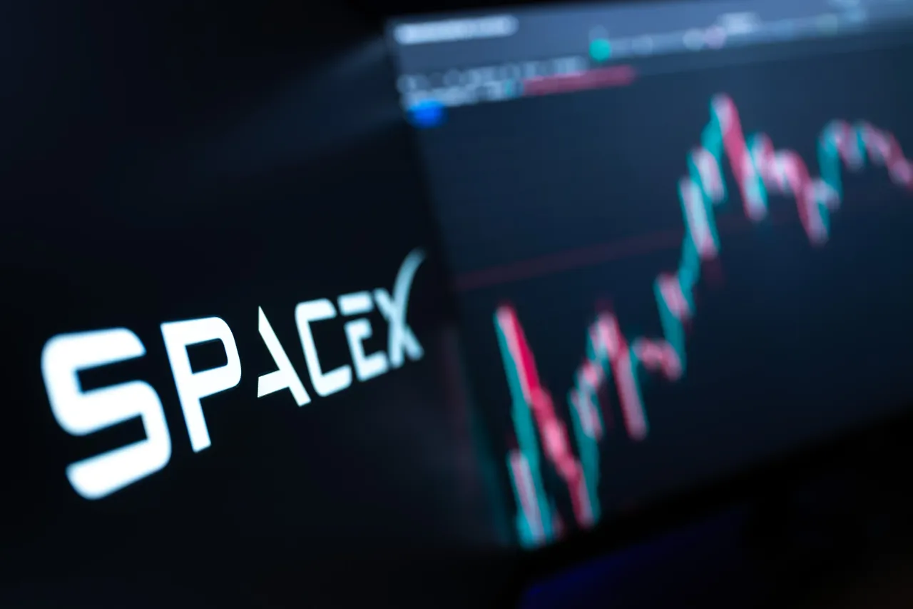 The logo of SpaceX, the U.S. aerospace, telecommunications, and AI company, is visible on a MacBook screen in front of a candlestick chart of SpaceX stock on TradingView. Photo: Silas Stein/dpa (Photo by Silas Stein/picture alliance via Getty Images)