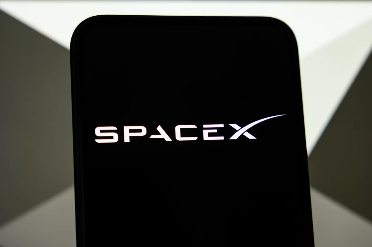 The SpaceX logo is displayed on a smartphone screen with the Cursor logo in the background, as SpaceX announces a partnership with Cursor, in Creteil, France, on April 22, 2026. (Photo by Samuel Boivin/NurPhoto via Getty Images)