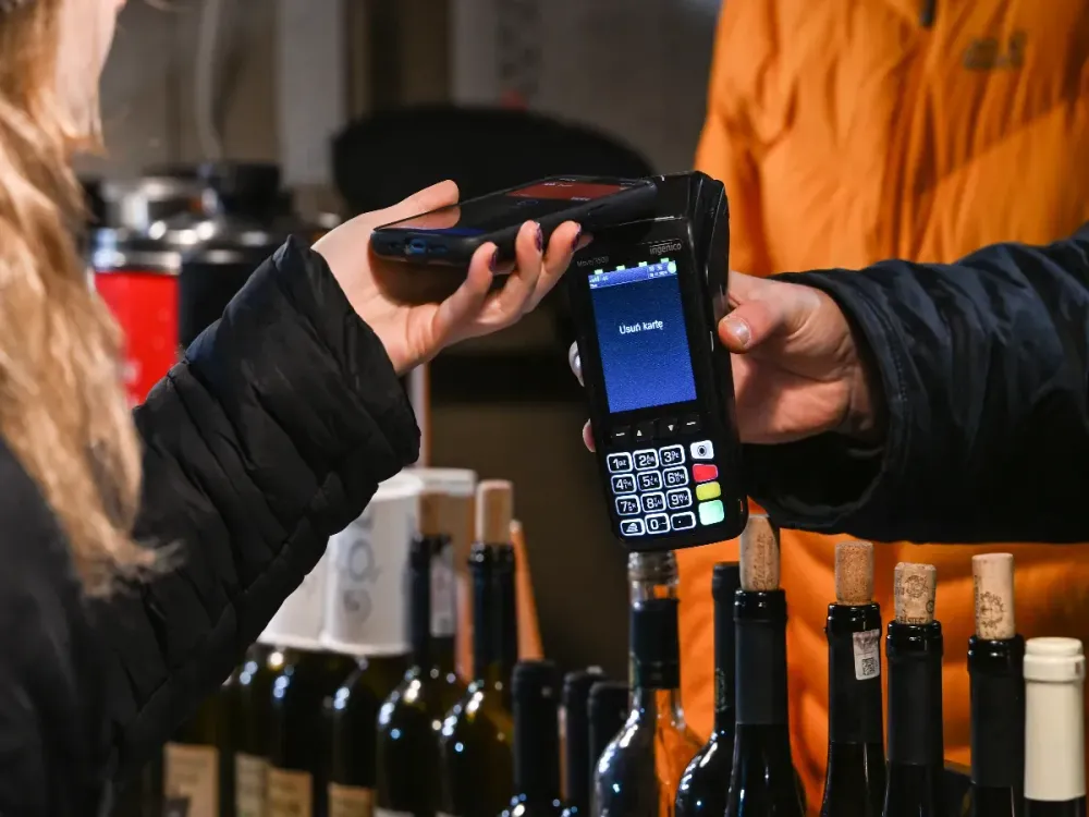 A lady pays for her wine purchase with her mobile phone at the Christmas Market in Krakow's UNESCO-listed Market Squarein Krakow, Poland. (Photo by Artur Widak/NurPhoto via Getty Images)