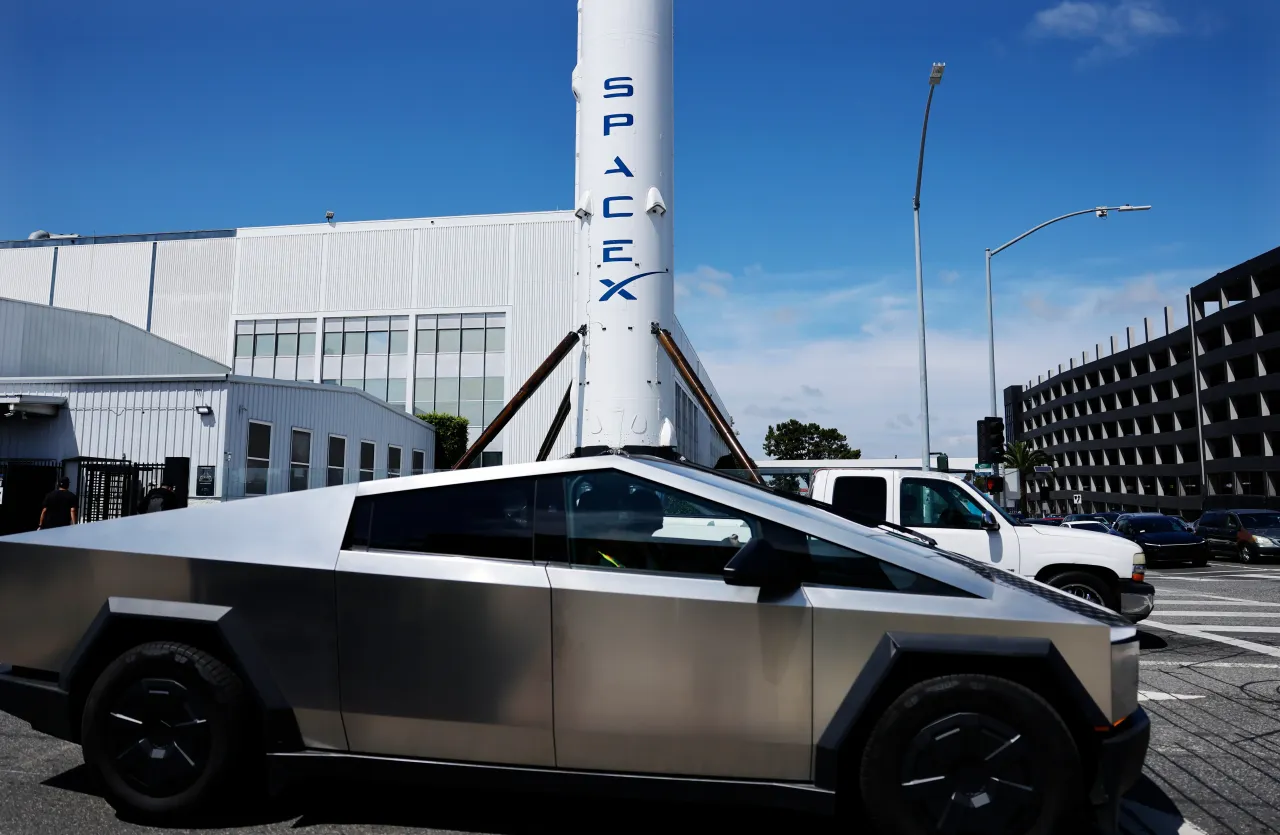 A Tesla Cybertruck is driven past a SpaceX Falcon 9 rocket displayed at a SpaceX facility on April 2, 2026 in Hawthorne, California. (Photo by Mario Tama/Getty Images)